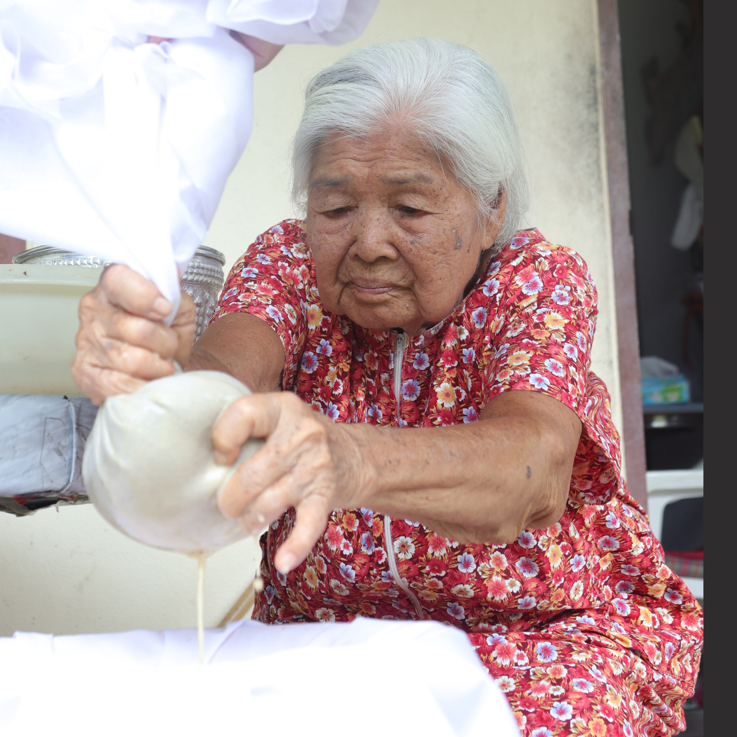 Elderly Koh Yor woman straining rice paste through cloth to make paeng luk-on herbal powder